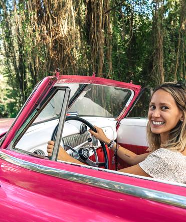 A tourist pretending to drive a classic American car in Cuba