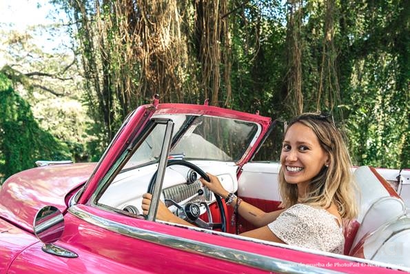 A tourist pretending to drive a classic American car in Cuba