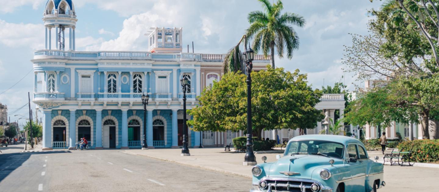 A blue classic car parked next to the Parque Jose Marti in Cienfuegos, Cuba