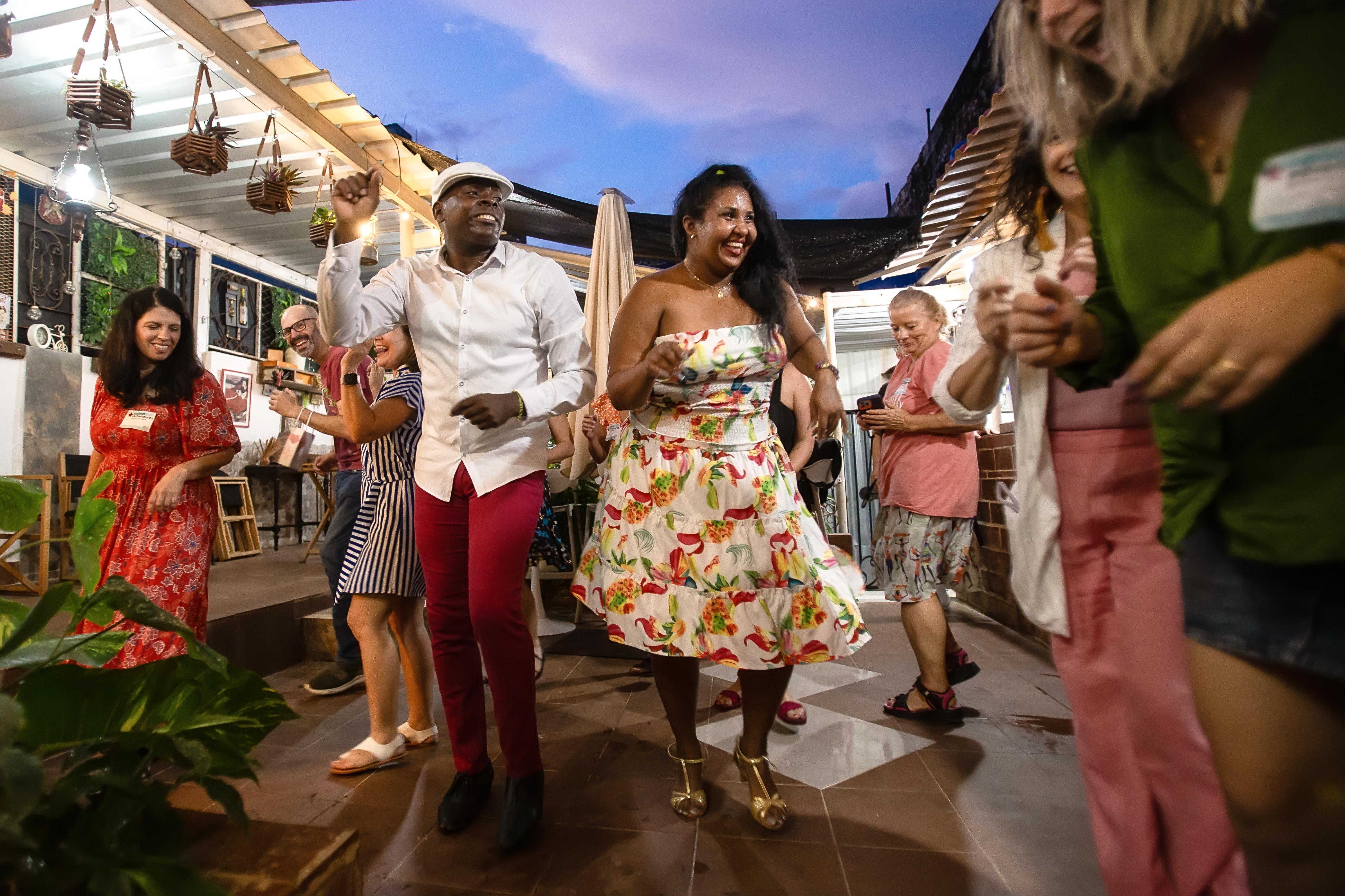 A cheerful Cuban couple teaches a group how to dance salsa on a rooftop patio
