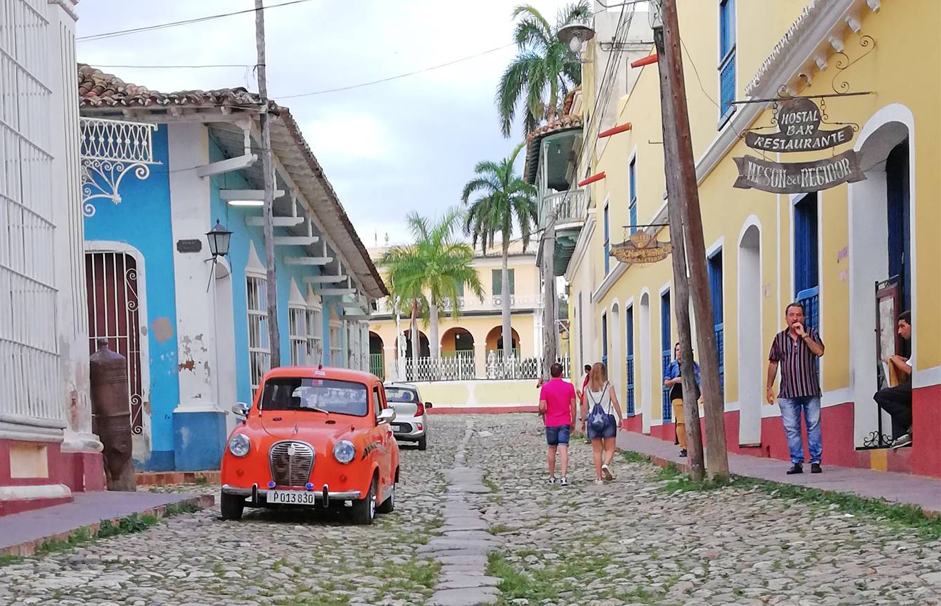 A cobblestone street in Trinidad, Cuba, with an orange 1950’s Austin a30 parked