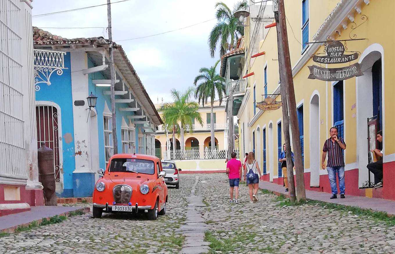 A cobblestone street in Trinidad, Cuba, with an orange 1950’s Austin a30 parked A cobblestone street in Trinidad, Cuba, with an orange 1950’s Austin a30 parked