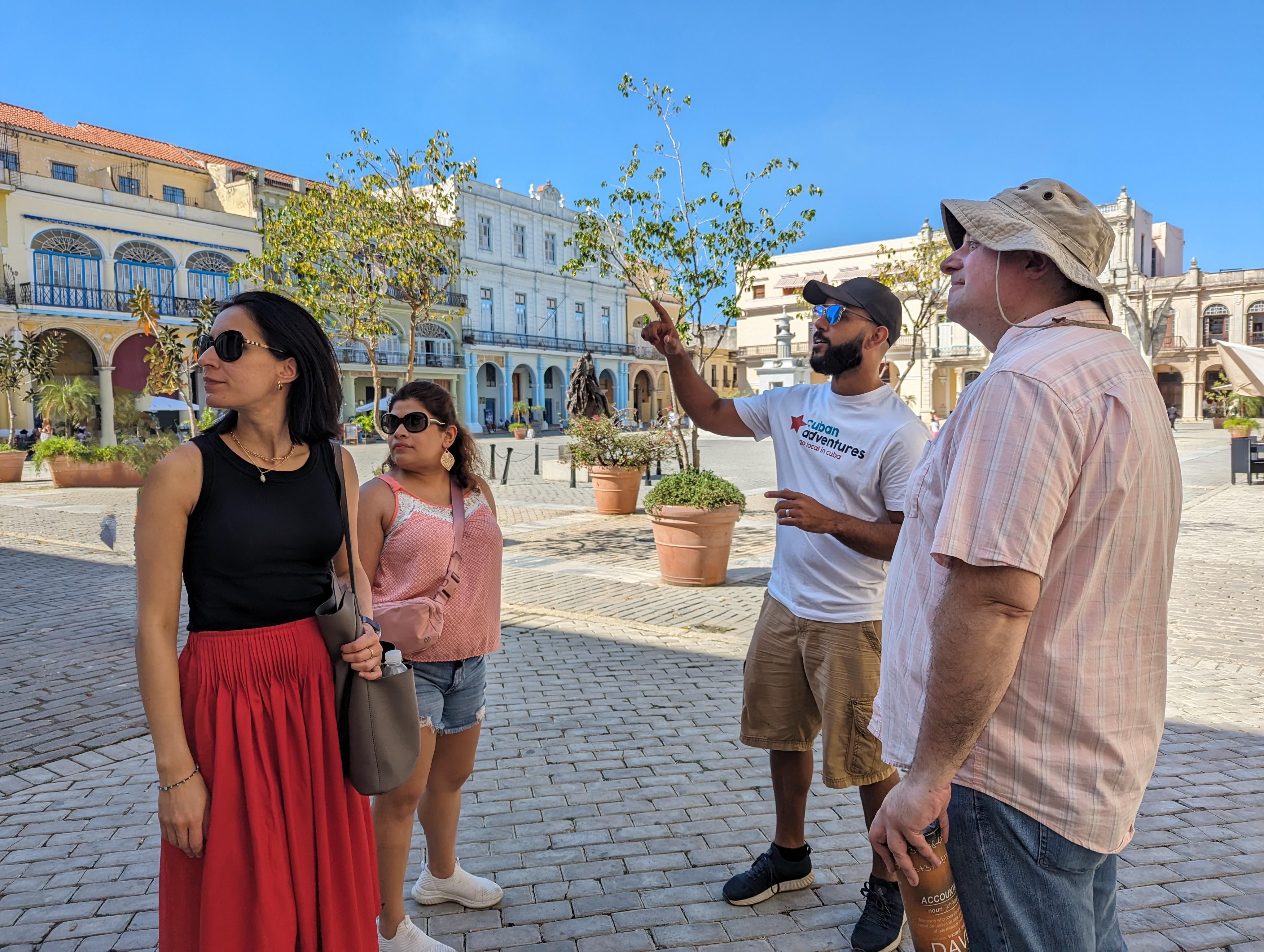 A Cuban Adventures tour guide points out Plaza Vieja highlights to a small group of tourists