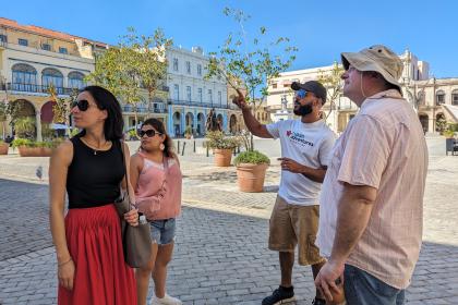 A Cuban Adventures tour guide points out Plaza Vieja highlights to a small group of tourists