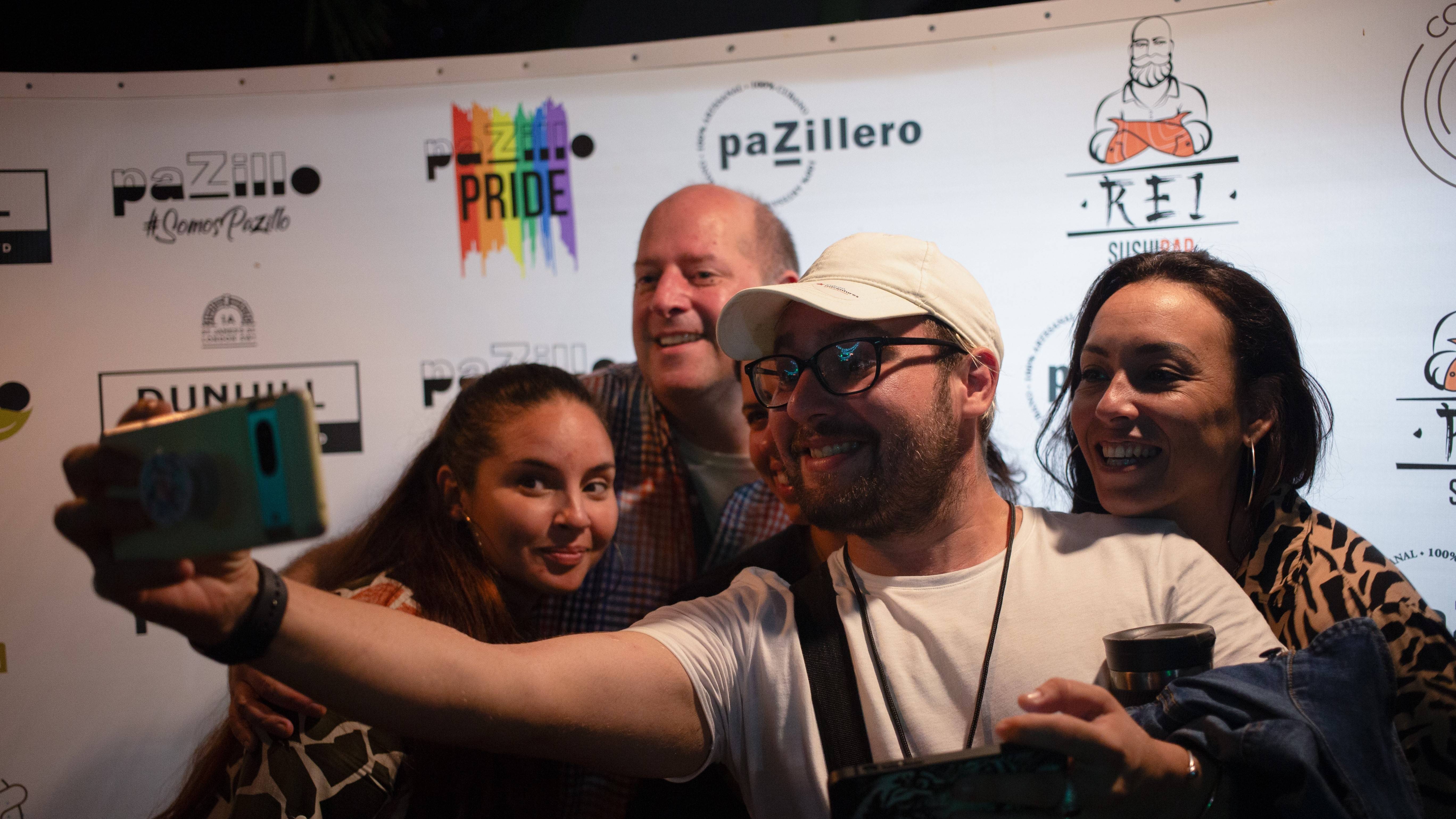 A group of four taking a selfie in front of a step and repeat A group of four taking a selfie in front of a step and repeat