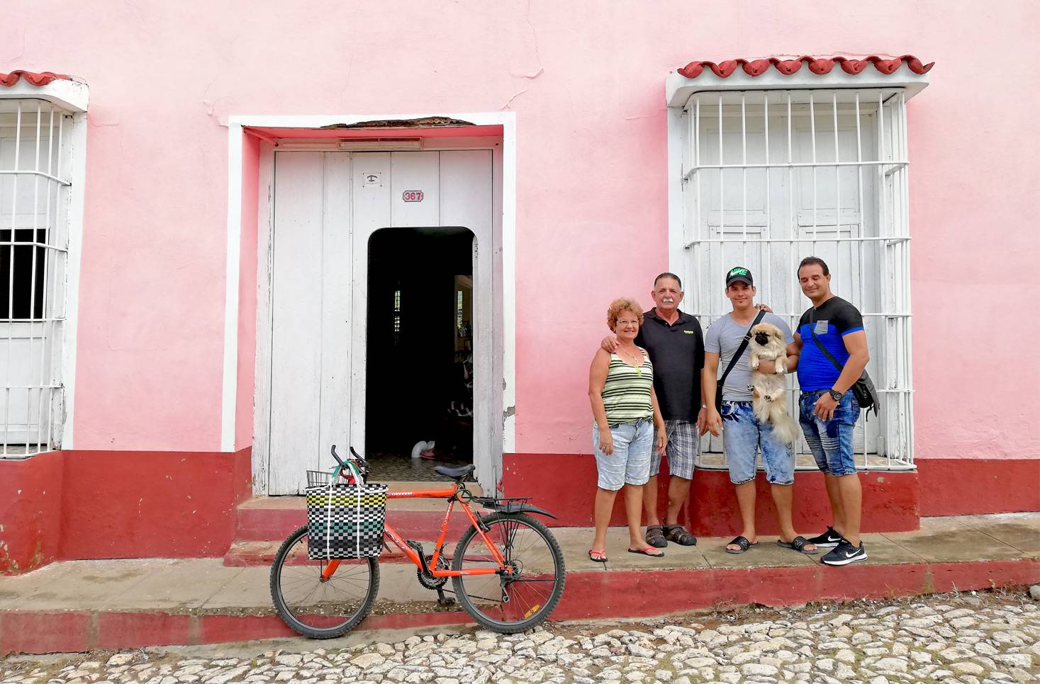 A local family poses in front of their pink casa particular in Trinidad, Cuba A local family poses in front of their pink casa particular in Trinidad, Cuba