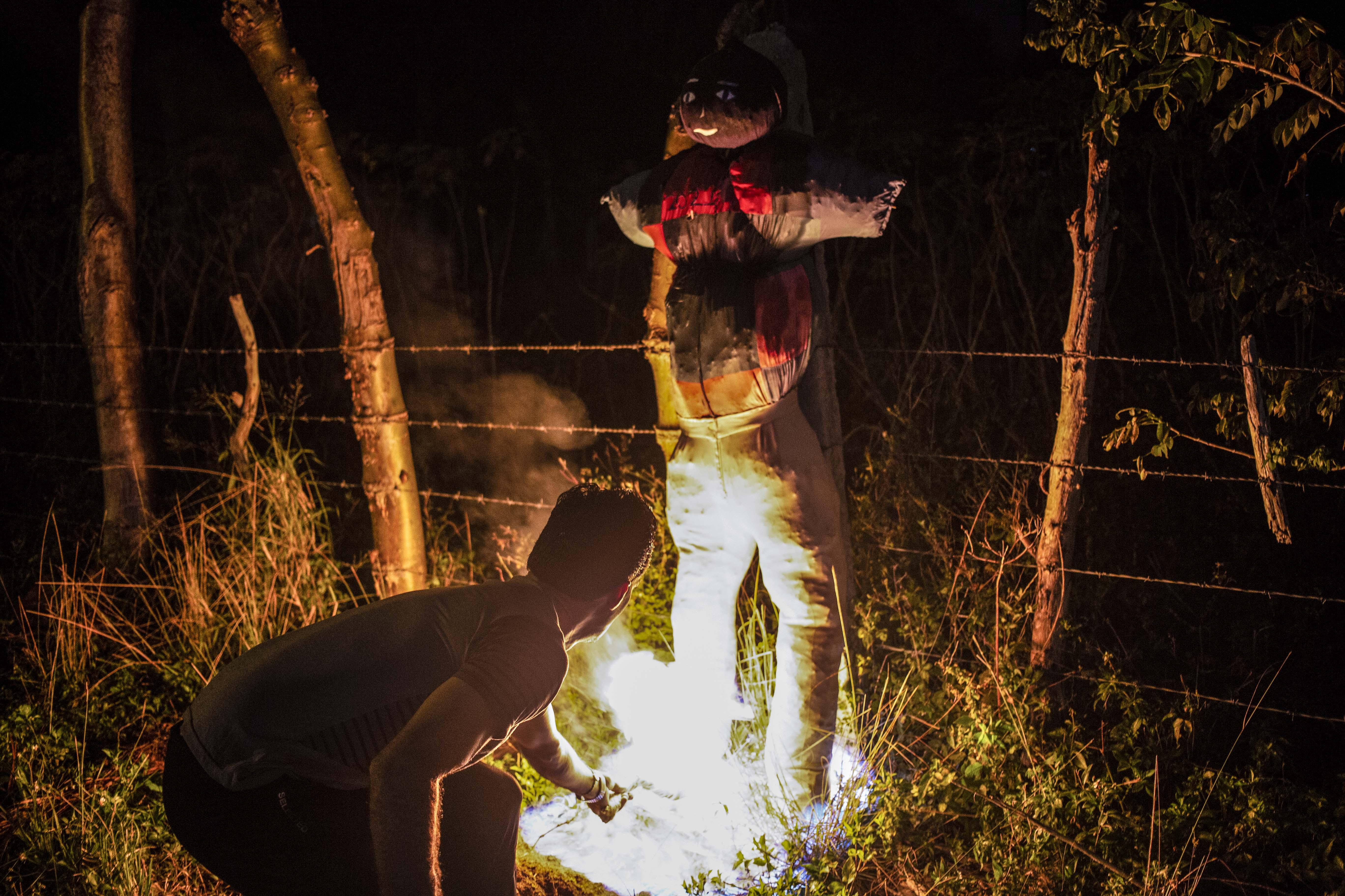 a man crouches to light fire to a life-sized homemade dummy on New Year’s Eve