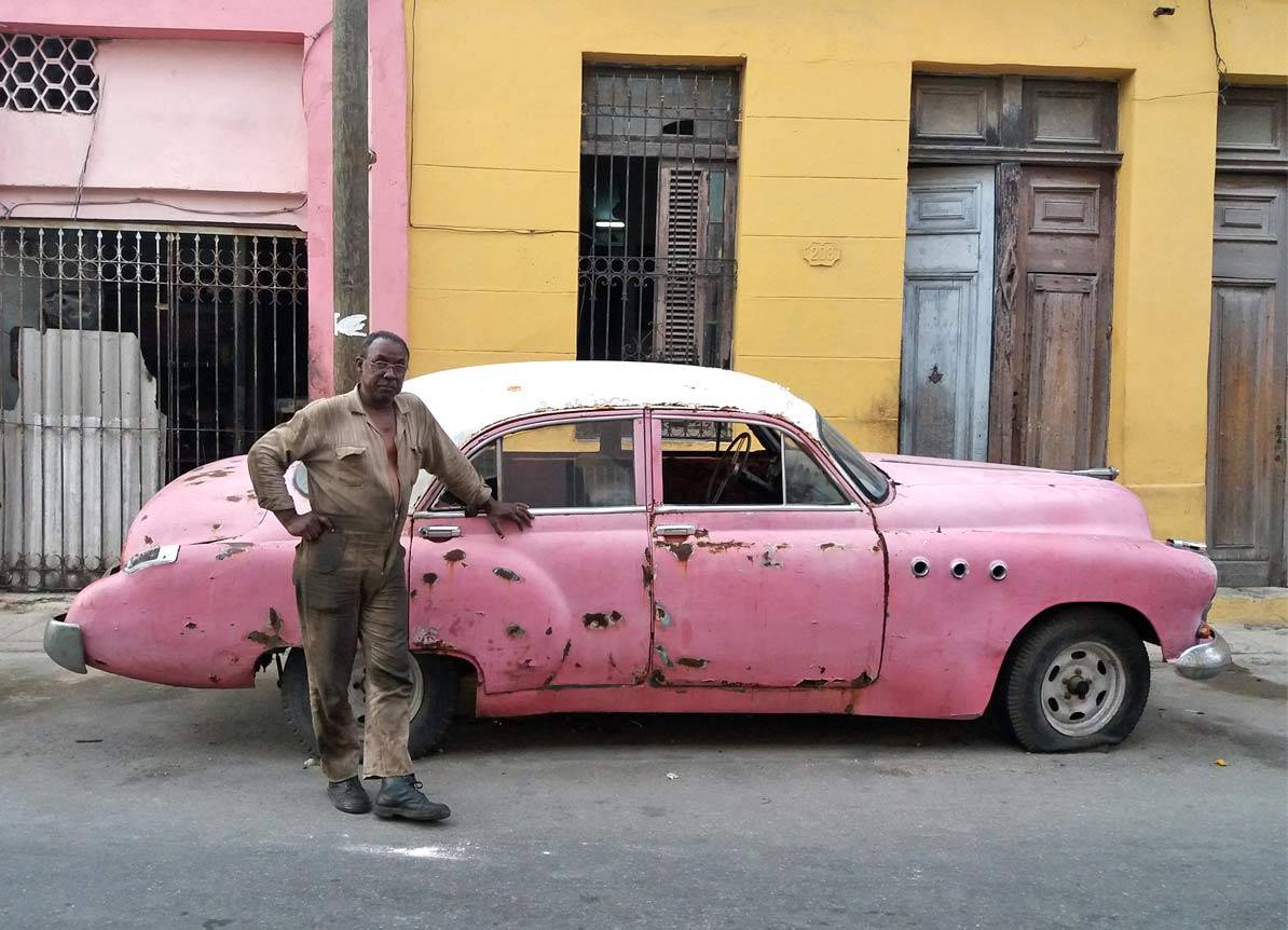 A mechanic in Havana working on the repair of a 1950s pink Buick A mechanic in Havana working on the repair of a 1950s pink Buick