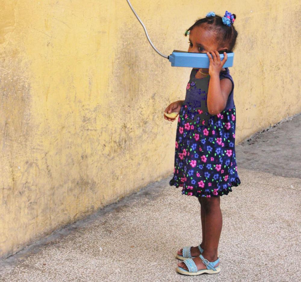 Uma menina pequena usando orelhão público em Cuba