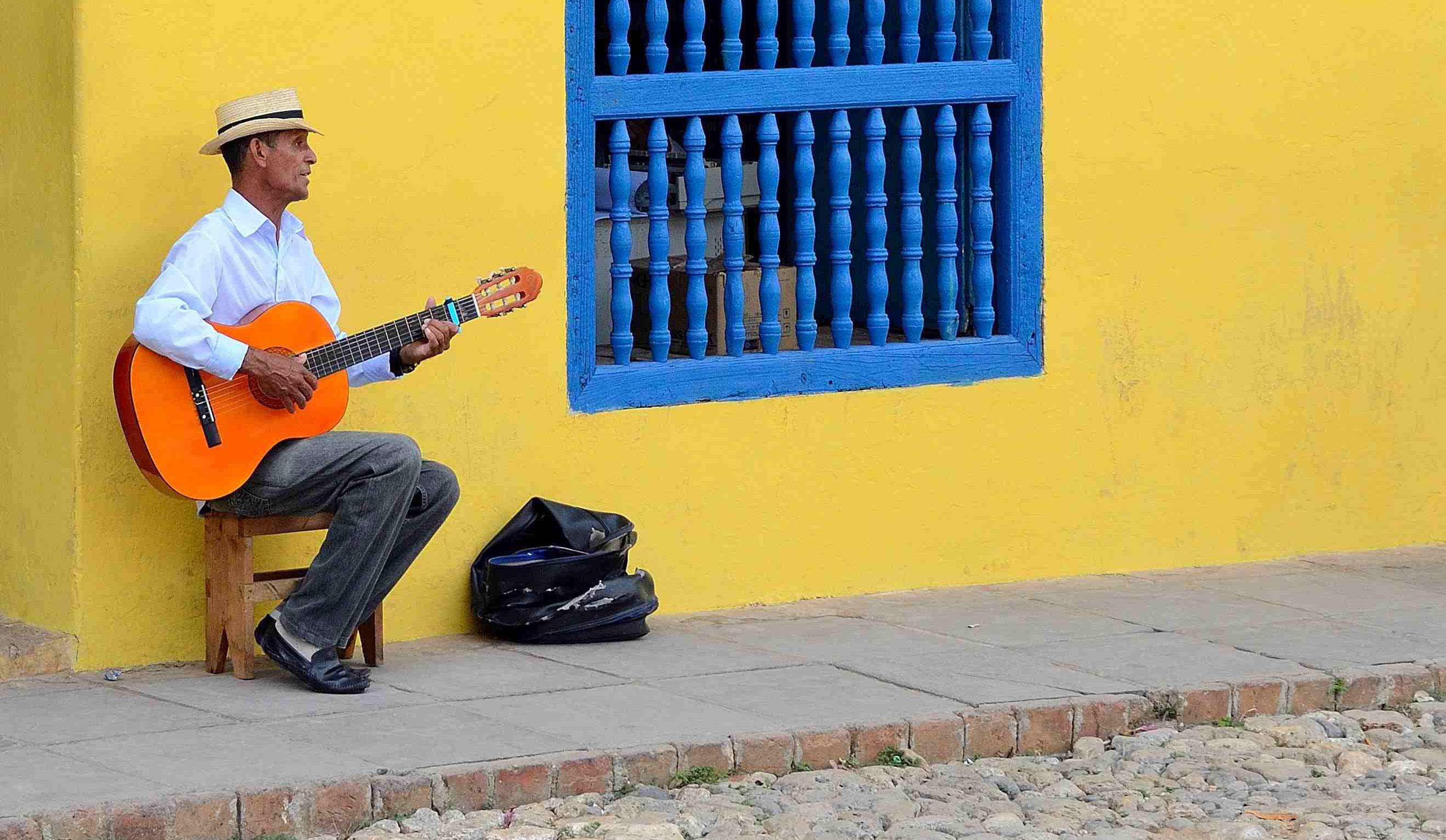 A trova musician plays his guitar outside a colonial building in Cuba