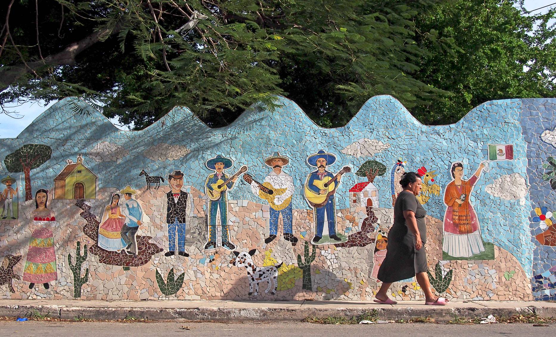A woman walks past a mosaic tiled mural in Fusterlandia, Jaimanitas, Havana