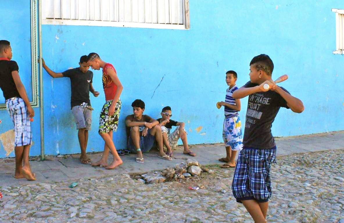 Although soccer is gaining popularity, you still see lots of ballgames on the streets boys play baseball in the street