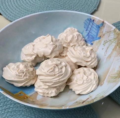 Beige colored merengues in a blue and tan ceramic bowl on blue circular place mats beige colored merengues in a blue and tan ceramic bowl on blue circular place mats