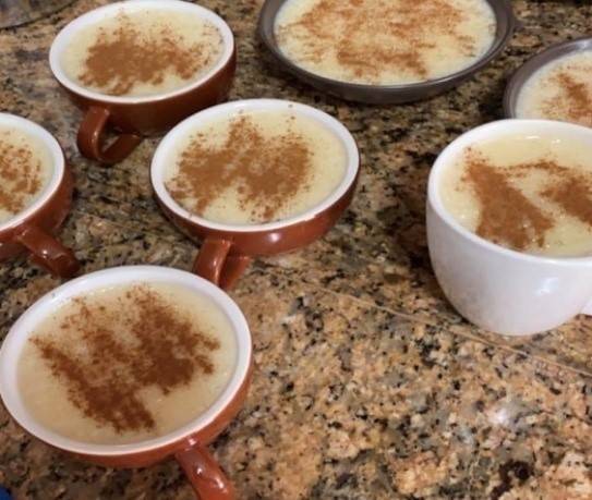 Brown mugs and bowls filled with rice pudding with cinnamon sprinkled on top brown mugs and bowls filled with rice pudding with cinnamon sprinkled on top