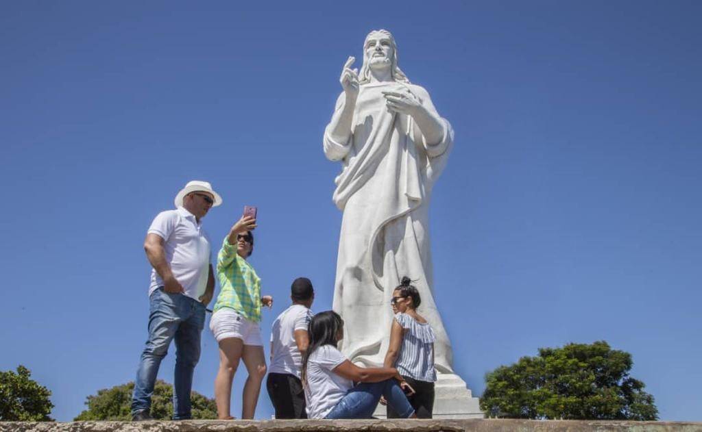 Christ of Havana, from here you will also get the most amazing bay views a group of people taking selfies in front of a tall white marble statue of Christ