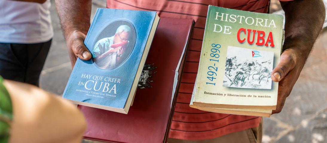 Close shot of arms of a person holding two books about Cuban history
