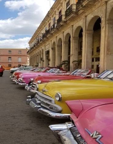 Convertibles to hire in Old Havana row of colorful classic convertible cars parked in front of building