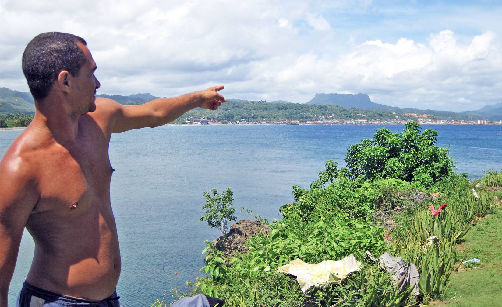 A local man in Baracoa, Cuba, points towards the Yunke tabletop mountain