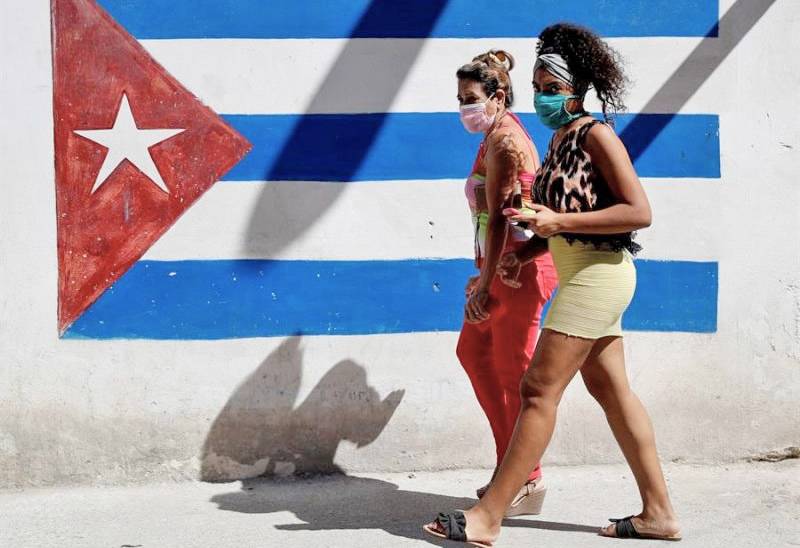 Cubans walk past a painting of a Cuban flag Cubans walk past a painting of a Cuban flag