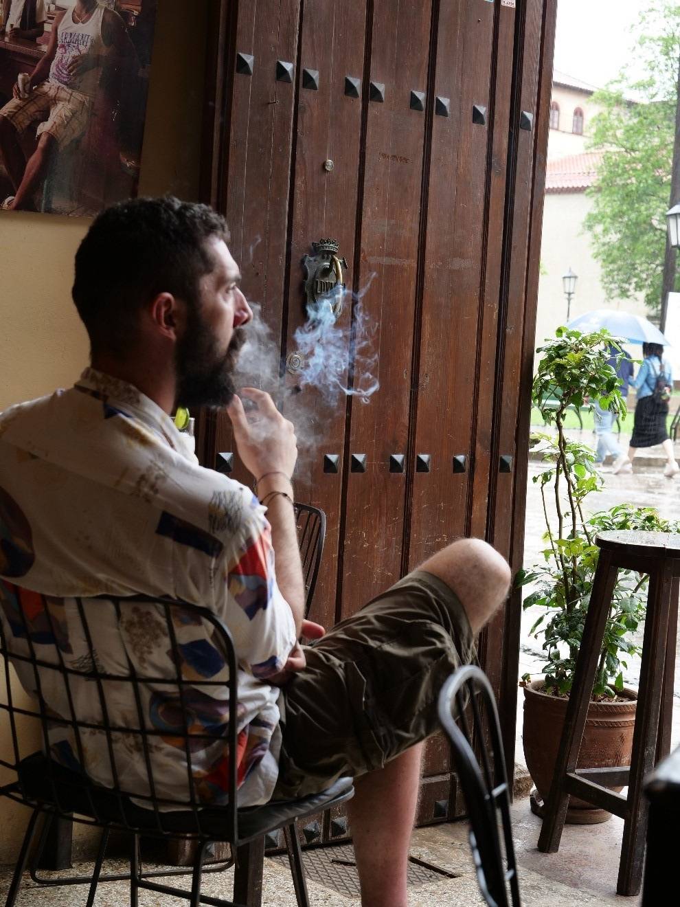 Enjoy a cigar in the moment you crave it. Photo credit: Saul Arizaga a man enjoys a cigar in a restaurant doorway