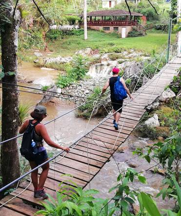 Trekkers cross a bridge in Topes de Collantes