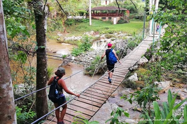 Trekkers cross a bridge in Topes de Collantes