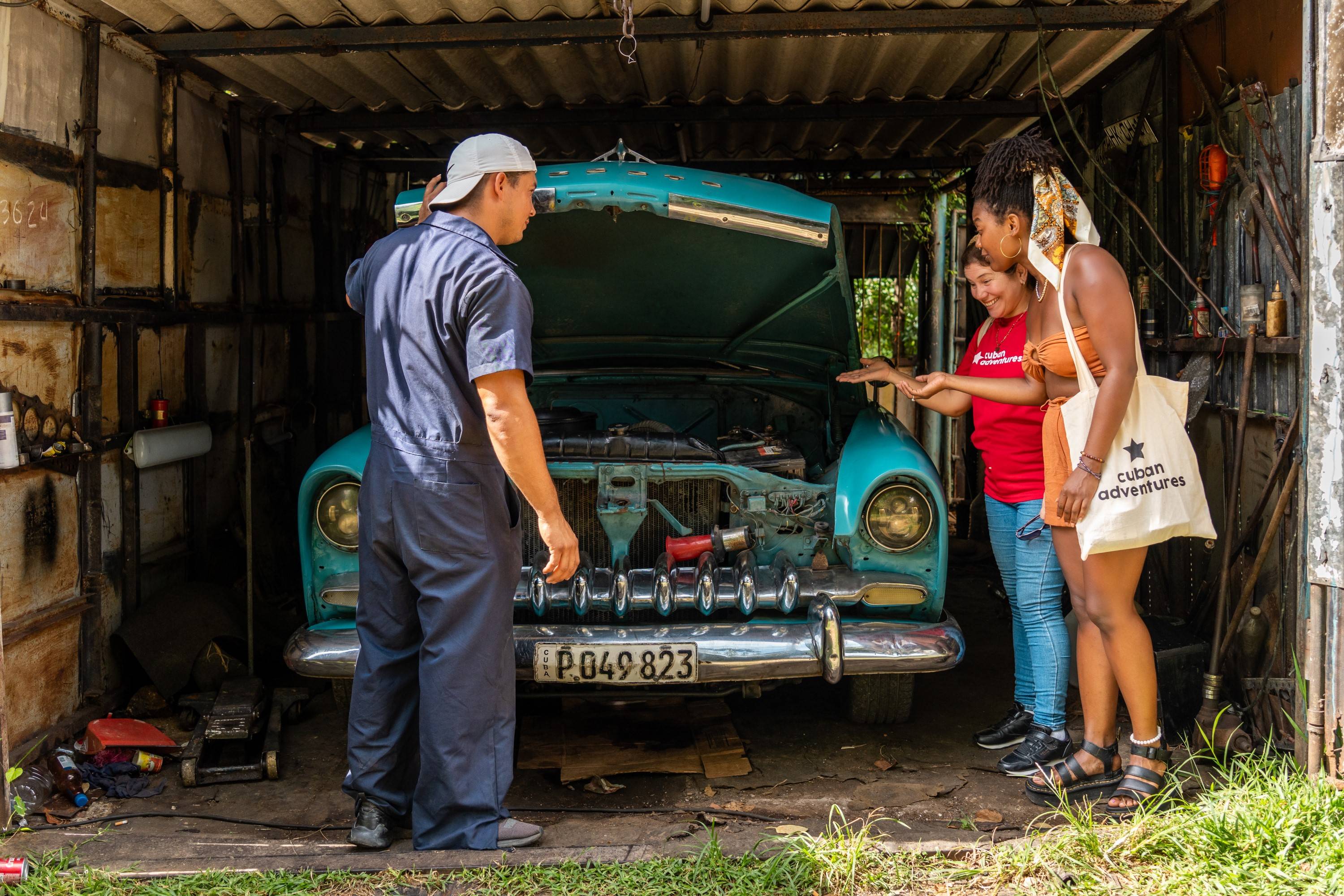 Group in front of blue Classic Car inside workshop Group in front of blue Classic Car inside workshop