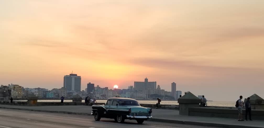 Havana's Malecon Image Source: Natalia de La Cavada/ Big Planet Adventures a classic car drives along a sea wall during sunset