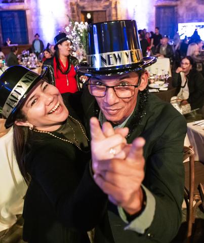 A happy couple dances while wearing black hats with Happy New Years on the band