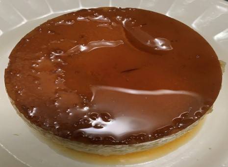 Round flan with a darkly caramelized top on a ceramic white plate round flan with a darkly caramelized top on a ceramic white plate