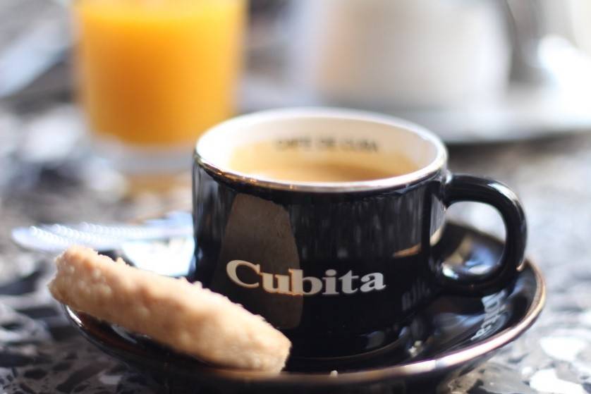 Sip a delicious mountain coffee grown in Topes a cup of coffee served on a saucer with a cookie