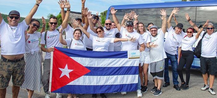 Cuban Adventures Team in front of Bus holding flag