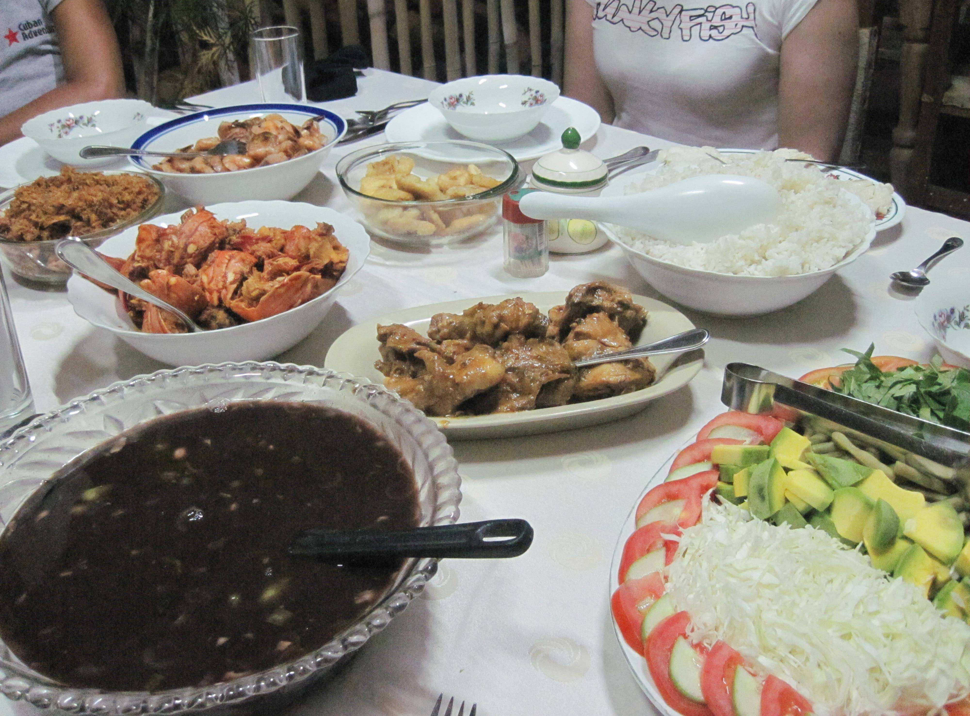 The dinner table at a private guesthouse in Cuba with bean stew (potaje), rice, seafood, fish, salad, and friend plantains. An assortment of dishes at a private guesthouse dinner