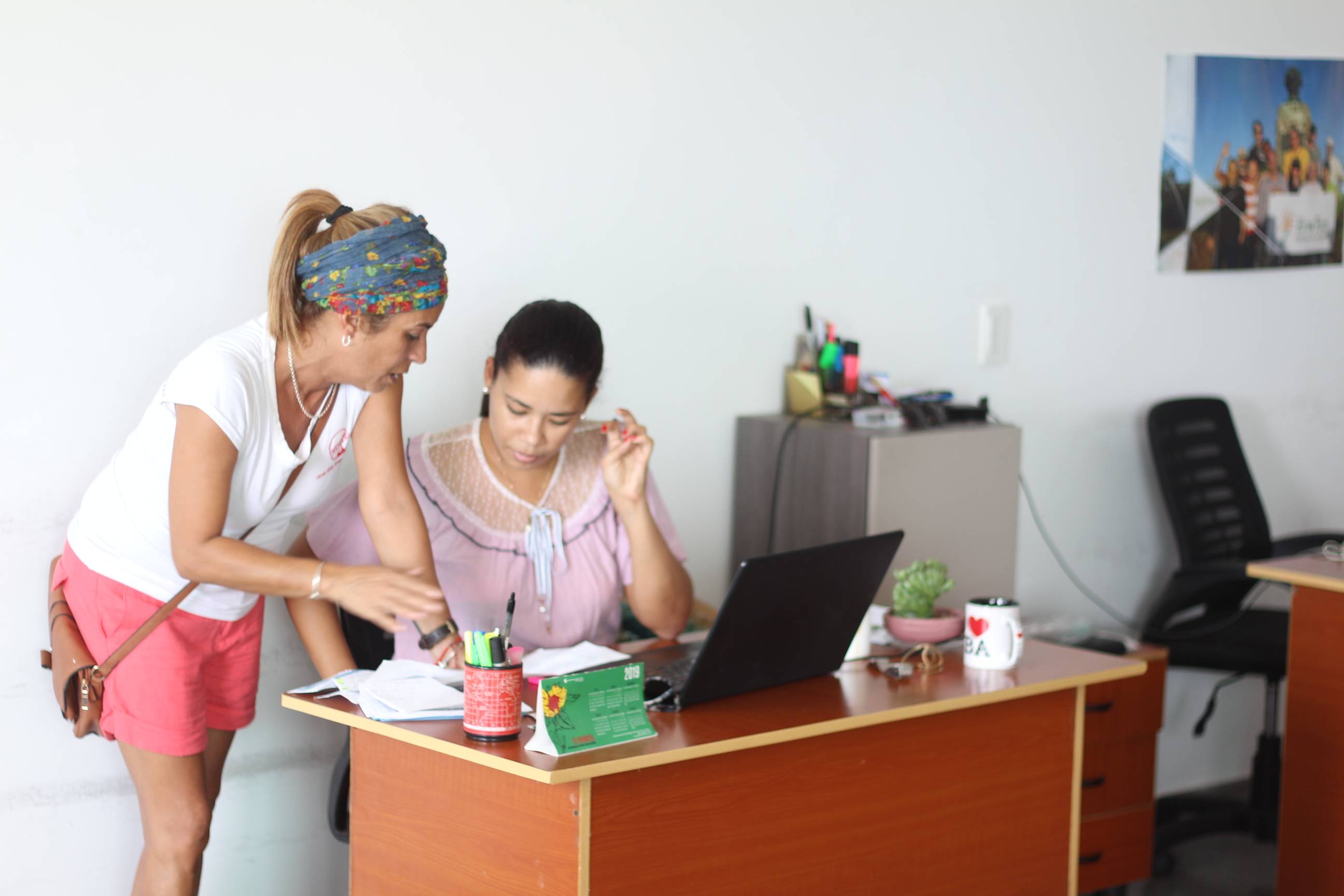 Two women converse at a desk in the Cuban Adventures office Two women converse at a desk in the Cuban Adventures office