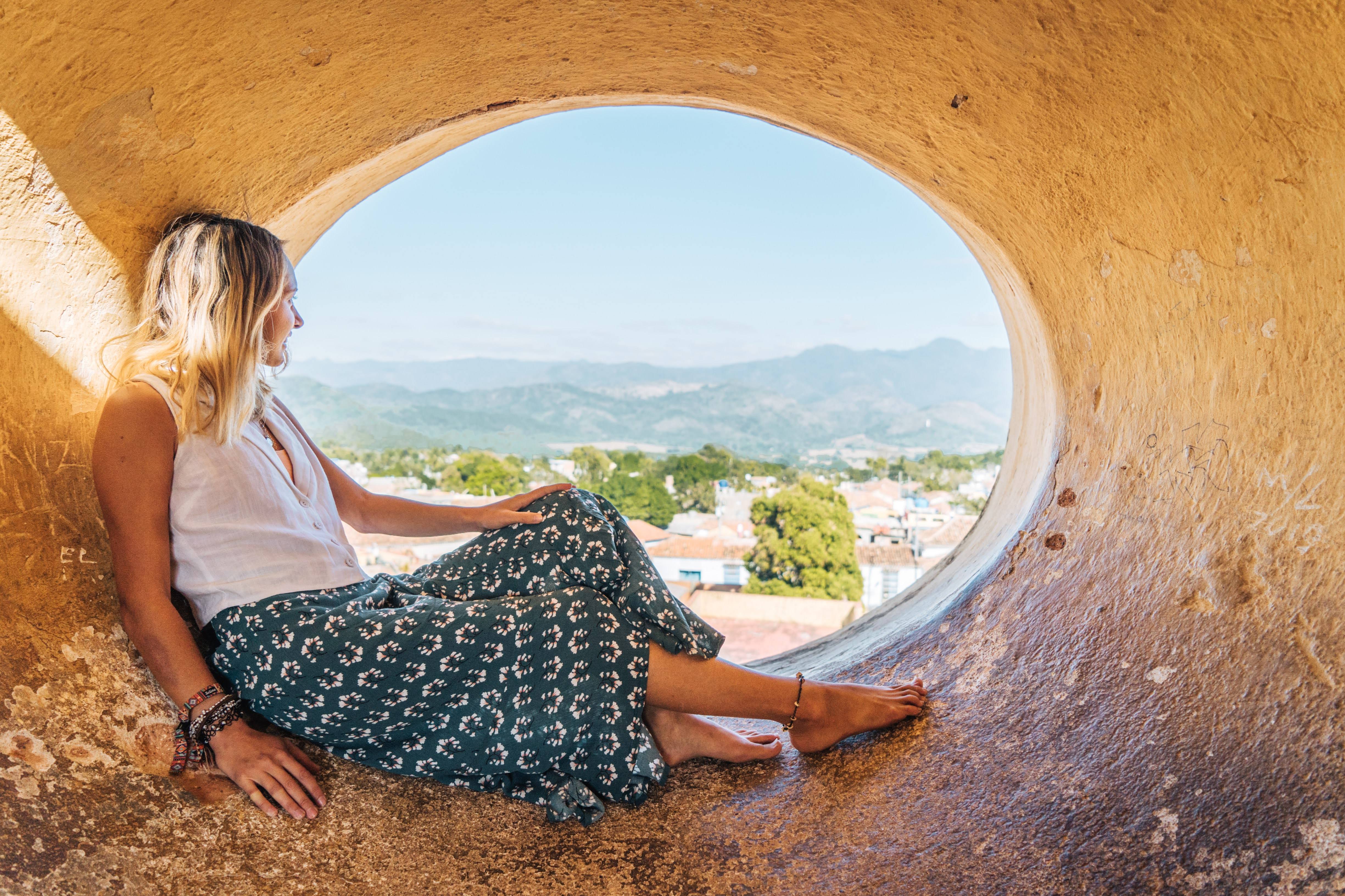 Woman sitting in a circular window looks out over Trinidad Woman sitting in a circular window looks out over Trinidad